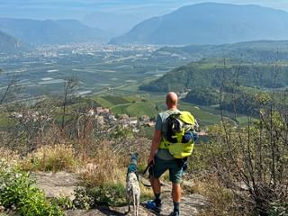 Wanderer mit Hund mit Panoramablick auf Südtiroler Landschaft