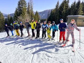 Group of skiers in colorful winter gear posing on snowy slope with forest and mountains in background at Eurofun Touristik Wintersporttag 2026.
