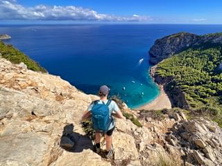 Hiker looks out over the turquoise-blue bay of Coll de Baix