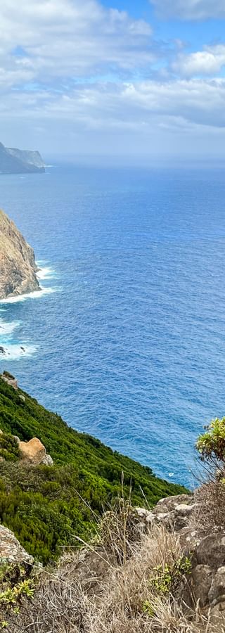 Steep coastal cliffs at Boca do Risco on Madeira's north coast with hikers on a trail, overlooking the deep blue Atlantic Ocean.