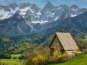 A wooden hut in the Triglav National Park with the mountain panorama in the background