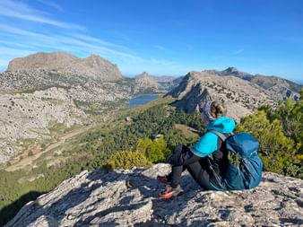 Hiker at the Coll de l'Ofre pass with a view of the Cuber reservoir