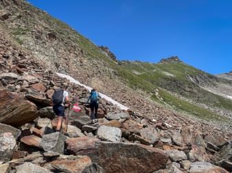Hikers climb over a stony section of path