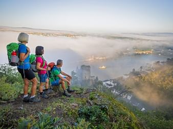 Wandergruppe beim Anblick auf die Burg Katz im Morgennebel