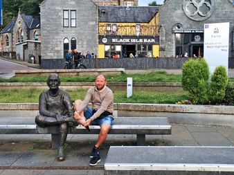 Man next to statue in Fort William at the end of the West Highland Way