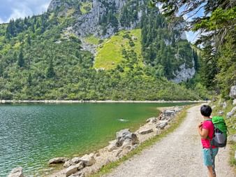 Wanderin mit Kind am Seeufer, im Hintergrund die Berge