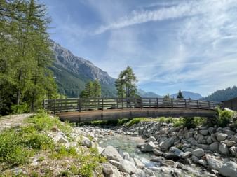 Holzbrücke mit Bergpanorama und Gebirgsfluss