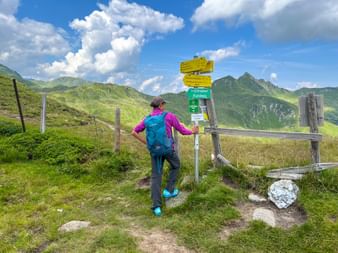 Wanderin vor Wegweisern am Zaun