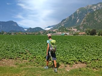 Hiker in front of a field in Gemona with mountain scenery in the background