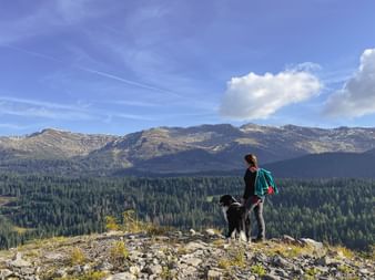 Hiker enjoys the mountain panorama of the Dolomites with her dog