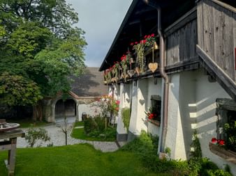 Traditional alpine building with wooden balcony decorated with red geraniums and heart ornaments in Schloss Kammer courtyard, Pinzgau.