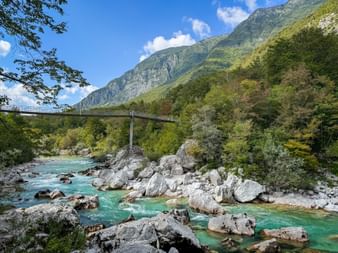 Hängebrücke über den türkisfarbenen Soča-Fluss mit weißen Kalksteinfelsen in den Julischen Alpen bei Trnovo ob Soči, Slowenien.
