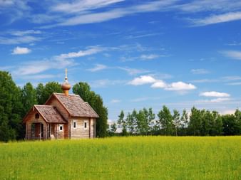 Eine Holzkirche in Finnland umgeben von Wiesen und Wald