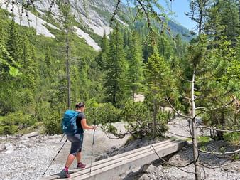 Hiker crosses stream with wooden footbridge