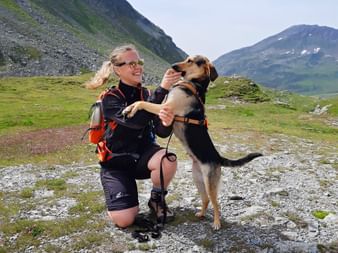 Wanderin mit Hund vor Bergkulisse