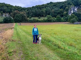 Wanderer mit Hund mit Wald im Hintergrund
