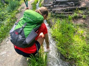 Hiker cools her hand in a small river