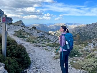Wanderin auf steinigem Pfad mit bergiger Aussicht