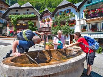 Hikers enjoy a refreshment at the village fountain of Hallstatt