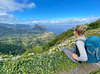 Hiker enjoys the view of the coastal landscape from the Miradouro da Portela viewpoint in Madeira
