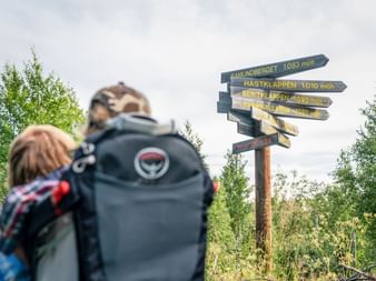 Zwei Wanderer blicken auf Wegweiser in Bruksvallarna
