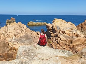 Hiker enjoys the great view of the red granite rocks and the sea