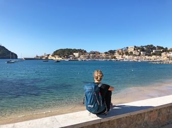 Hiker sitting on a wall with a view of Soller