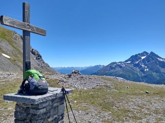 Summit cross with panoramic view and green backpack