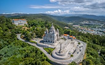 Aerial view of Basilica da Santa Luzia in Viana do Castelo, surrounded by green hills and overlooking the city and mountains.