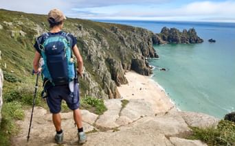 Wanderin genießt von einer Klippe den Blick auf den Pedn Vounder Beach