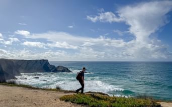 Wanderer mit Rucksack auf Küstenklippe mit Blick auf den Atlantik am portugiesischen Jakobsweg von Porto nach Santiago de Compostela.