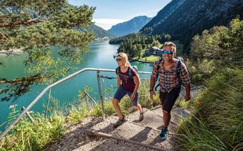 Happy travellers on a hiking trail with a view of the lake