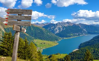 Hiking signpost with a view of Lake Reschen