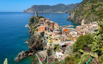 Vernazza village with colorful houses on rocky cliffs overlooking the Mediterranean Sea, with a small harbor and historic tower in Cinque Terre.