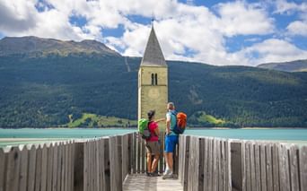 Hikers have a view of the turquoise Lake Resia with its sunken church tower