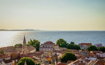 Aerial view of Zadar's old town with red-tiled roofs, a church tower, and the Adriatic Sea in Northern Dalmatia, Croatia.