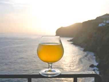 Traditionelles Getränk Poncha bei Sonnenuntergang mit Blick auf Küste und Meer