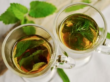 Herbs in hot tea water in a glass cup