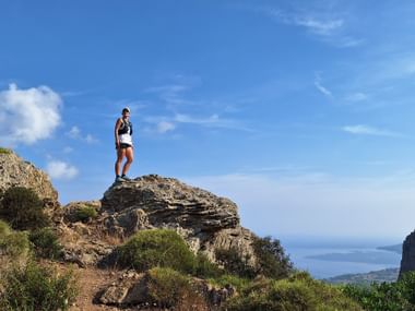 Wanderin auf Gipfel mit Meer im Hintergrund
