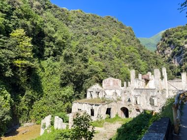 Steinruinen alter Industriegebäude in Toscolano Maderno, umgeben von grünen Bergen unter blauem Himmel am Gardasee.