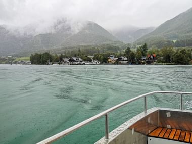Boat on Lake Attersee in rainy weather and with a view of fishermen's houses