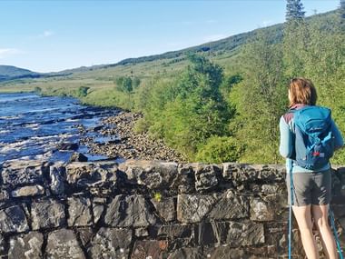 Hiker standing on a bridge in Bridge of Orchy looking out over the landscape