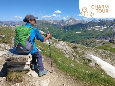 Hiker on a mountain with peaks in the background