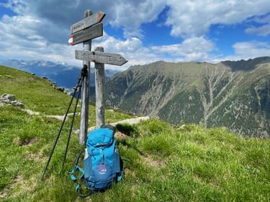 Backpack at the signpost in front of a mountain backdrop