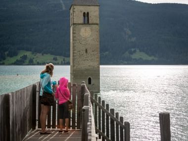 Mom and daughter look at the church tower in the lake