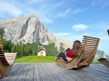 Hiker in a wooden deckchair with a view of the mountains