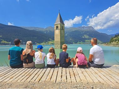 Family takes a break from hiking on the shores of Lake Resia
