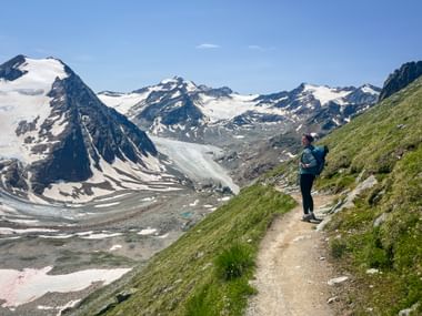 Hiker on a hiking trail with a view of the Alps