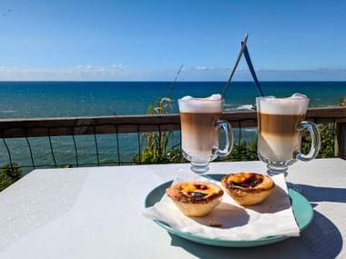 Kaffee und Pastel de Nata mit Meeresblick