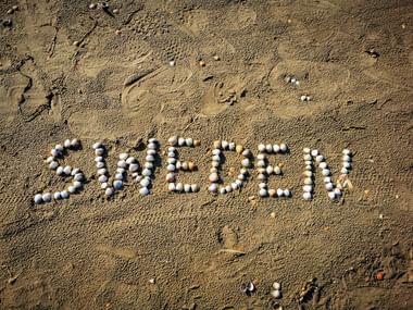 Das Wort SWEDEN mit bunten Kieselsteinen auf sandigem Strand in Westschweden geschrieben.